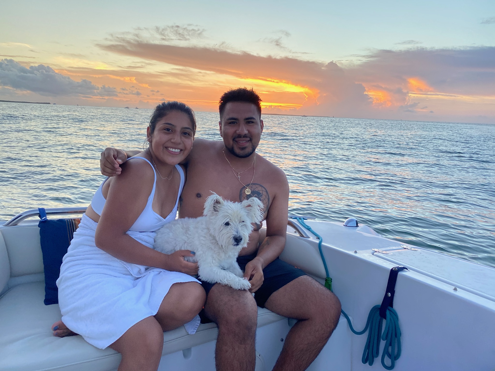 couple with dog on the boat, sunset in the back